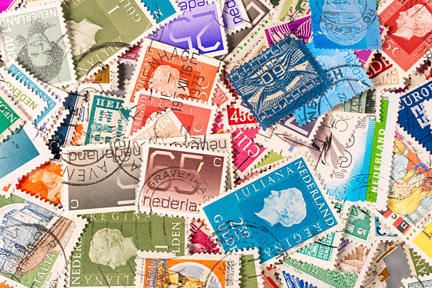 Many postage stamps are spread out on a table. They come from different nations and feature various designs and colors. The stamps show their unique features and styles.
