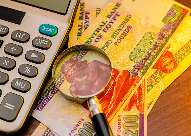 istock An image featuring Egyptian 200 pound banknotes, a calculator, and a magnifying glass on a wooden surface. It emphasizes financial analysis, currency examination, and Egyptian economic themes. 2250318067