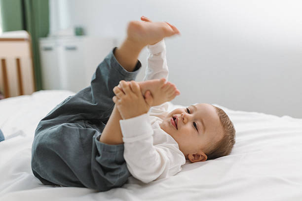 istock Playful baby relaxing on a soft white bed 2250318207