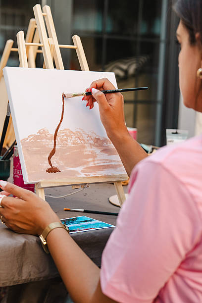 istock Woman painting during art class, creating landscape on canvas 2250321635