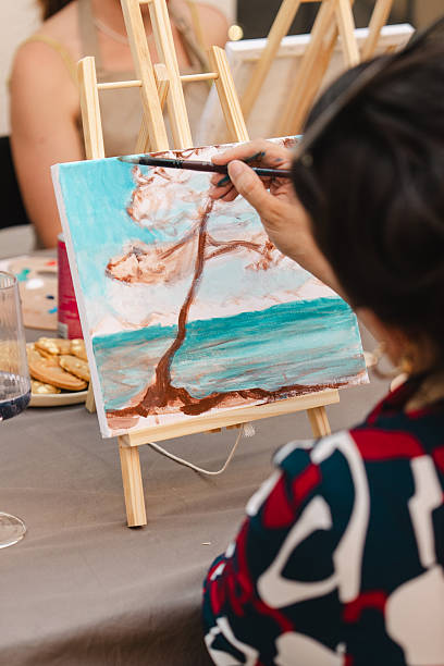 istock Art class participant painting a landscape on canvas with a brush 2250321863