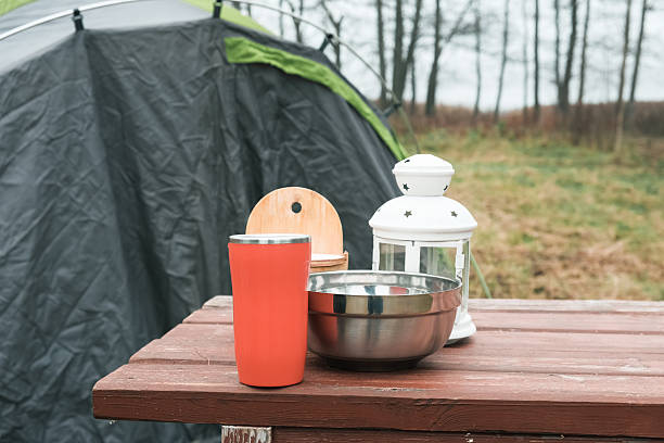 Lakeside camping scene, Camp setup by tranquil waters, Arranged campsite area near peaceful lake forest. Serene campsite prepared for outdoor meal experience. Quiet. Campground basic cooking amenities.  Camping travel background. Display touristic, fishing, hunting product items ad. Design element visual layout. Copy space. Outdoor travel stage.