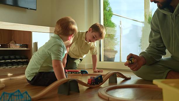 istock Father and Sons Playing with Toy Train Set 2250325512