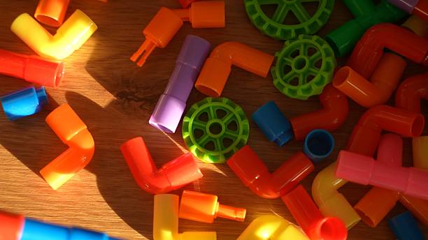 Brightly Colored Plastic Building Pipe and Wheel Toys Scattered on a Wooden Floor,Creating a Playful and Creative Background For Childhood Games and Learning