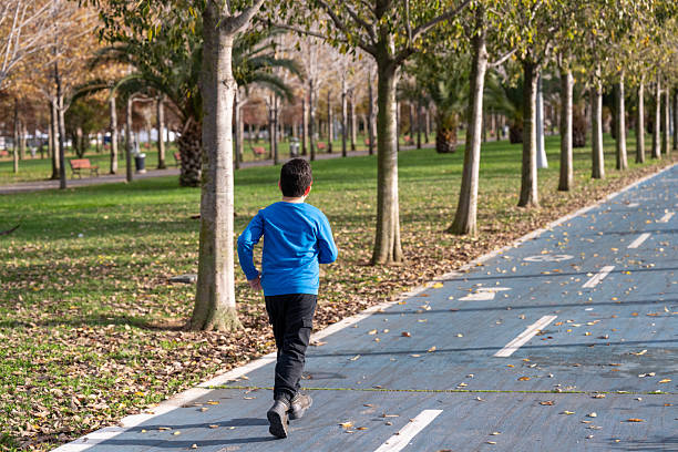 Small and overweight boy jogging in the park