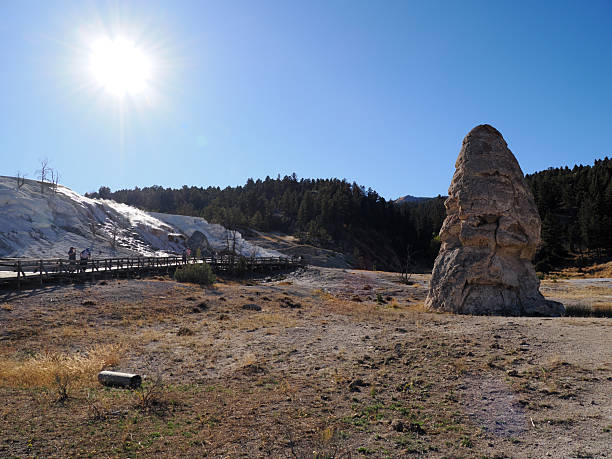 Mammoth Hot Springs, Yellowstone NP, WY - Sep 23, 2025: The distinctive Liberty Cap rock formation, a dormant hot spring cone, under a bright sunburst.