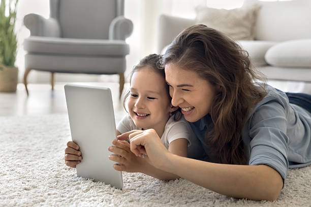 istock Smiling mother lie on floor with daughter use digital tablet 2250354583