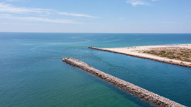 istock Serene coastal view featuring a stone jetty extending into calm turquoise waters, ideal for relaxation and beach activities. Tavira Portugal Algarve 2250356166