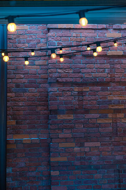 istock Cozy glowing string lights on a textured red-brick wall backdrop. Warm illumination creates a urban ambiance on rustic bricks 2250361675