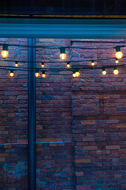 istock Cozy glowing string lights on a textured red-brick wall backdrop. Warm illumination creates a urban ambiance on rustic bricks 2250361723