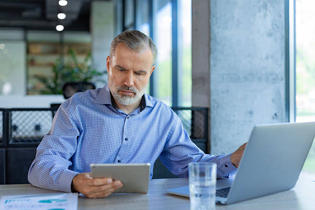 istock Handsome mature businessman manager sitting in office with tablet computer 2250362127