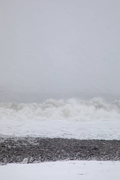 istock Winter sea waves breaking on pebble beach during snowfall in overcast weather 2250369688