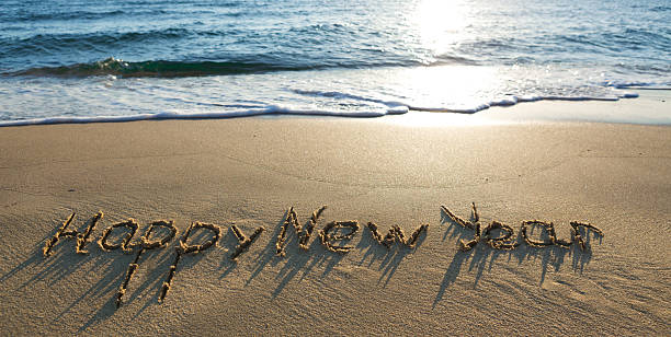 istock Happy New Year lettering on the sunny beach sand. 2250377369