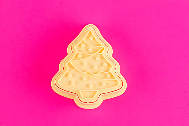 plastic molds for making Christmas cookies on a pink background