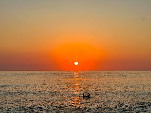 istock Silhouettes Sitting on Paddleboard During Vibrant Orange Ocean Sunset 2250395195