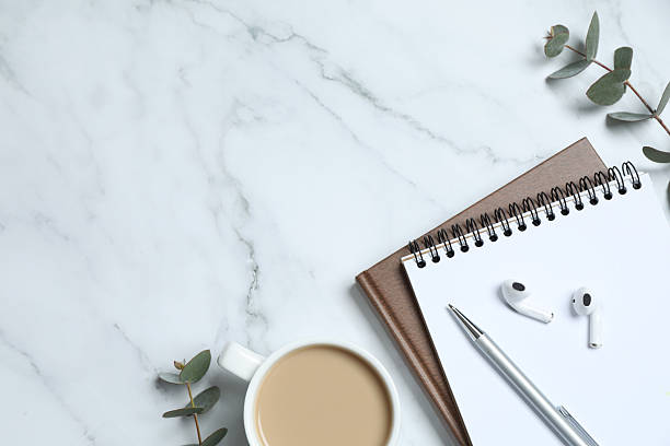 istock Workplace with planner, pen, cup of coffee and eucalyptus on marble background with blank space 2250395311