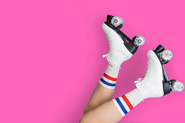 istock Retro white roller skates on legs with striped socks against pink background 2250399632