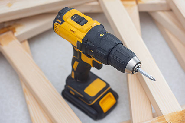 istock Cordless drill screwdriver stands on wooden planks during carpentry assembly work. Close-up of a construction tool used for woodworking and furniture building. 2250403644
