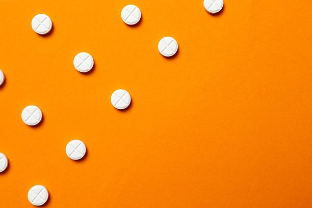 istock White medical pills on a colored background 2250404519
