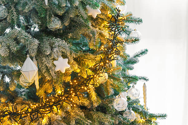 istock Snowy frosted Christmas tree branches with ornaments on warm string lights illumination background 2250407941