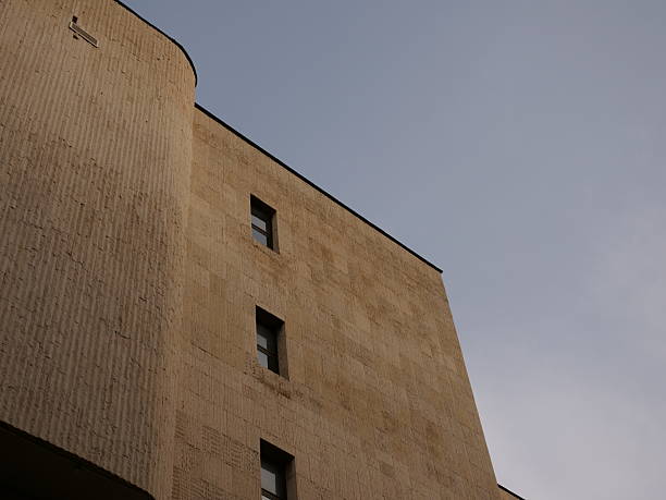 istock Brutalist architectural concrete building facade detail with textured raw materialagainst a blue sky. 2250408201
