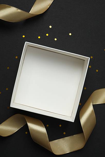 istock Open white box with golden silk ribbon on black background 2250411462