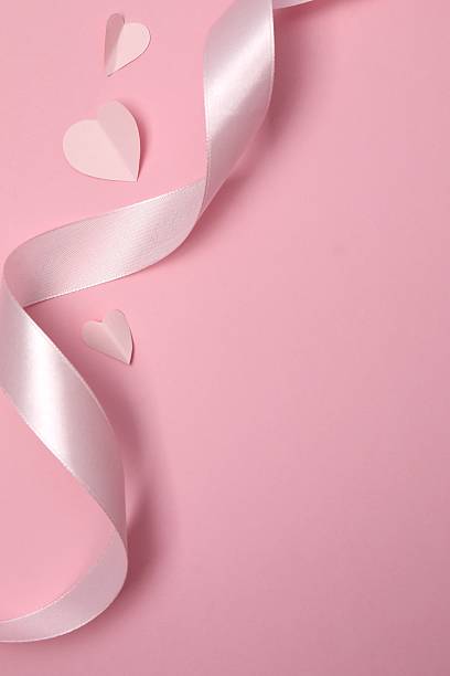 Pink hearts with silk ribbon on color background