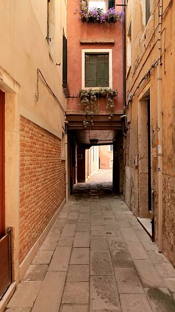 istock Narrow, empty Venetian alleyway with historic architecture, brick wall, and arched passage. Perfect for travel, architecture, and tranquil city exploration concepts. 2250411731