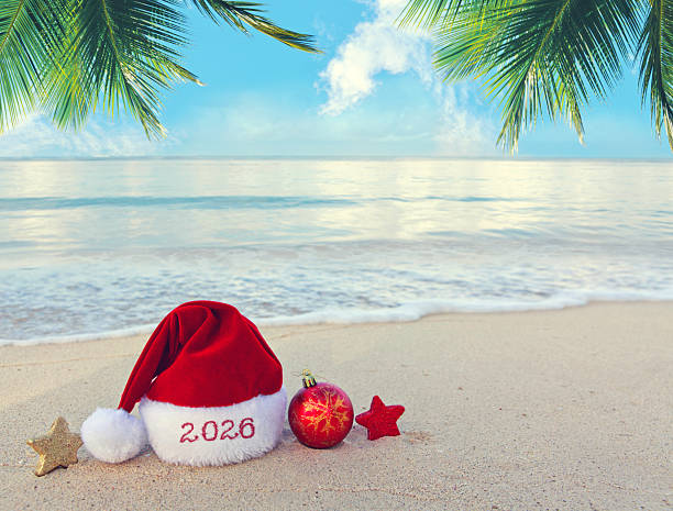 istock Merry Christmas background with red hat and decorations on Caribbean sand. 2250411961