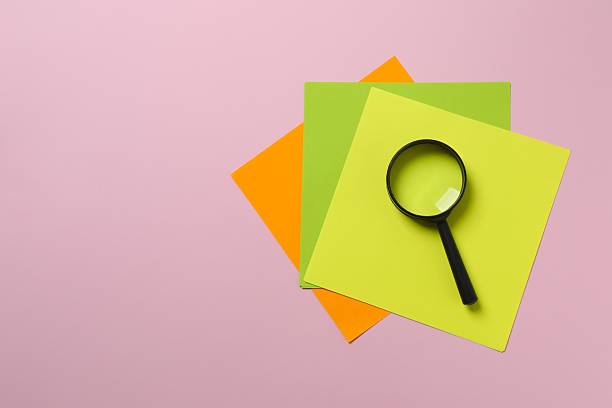 Magnifying glass with paper stickers on color background
