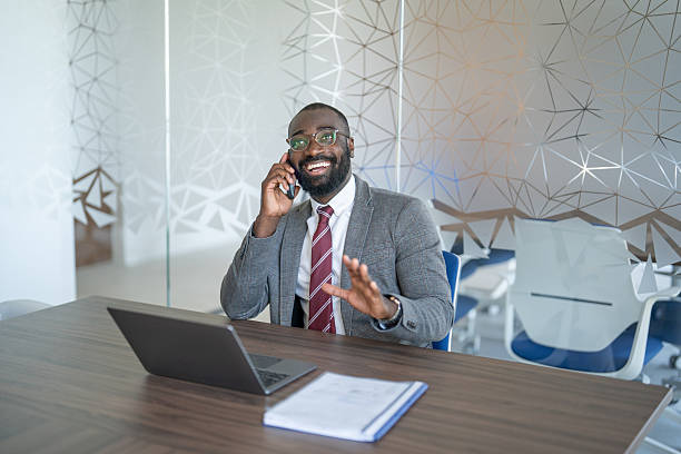istock Smiling businessman talking on phone and gesturing in modern office 2250419930