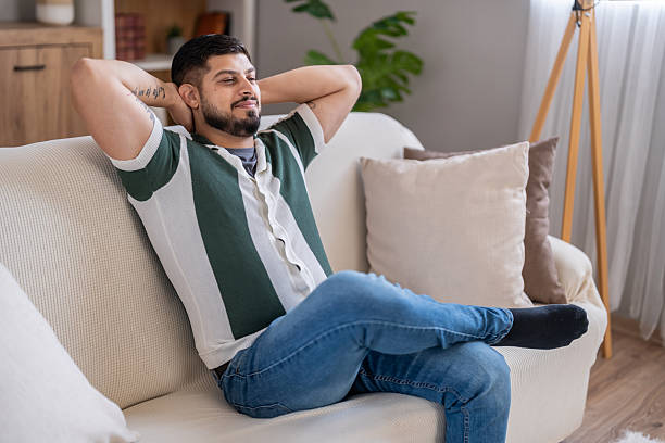 istock Man relaxing on couch at home enjoying leisure time 2250419970