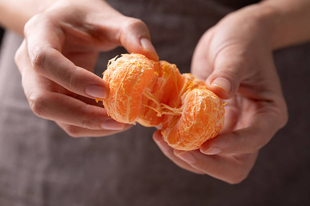 istock Mandarin orange fruit holding by hand and eating 2250423983