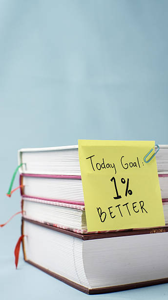 istock Stacked books with a 1% better motivational sticky note on blue background 2250426066