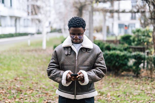 istock Young black man using smartphone outdoors in modern residential district 2250432145