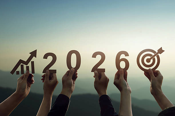 Hands holding 2026 numbers with growth chart and target icon at sunrise, symbolizing economic planning, business goals, financial strategy, long term vision, future success and growth.
