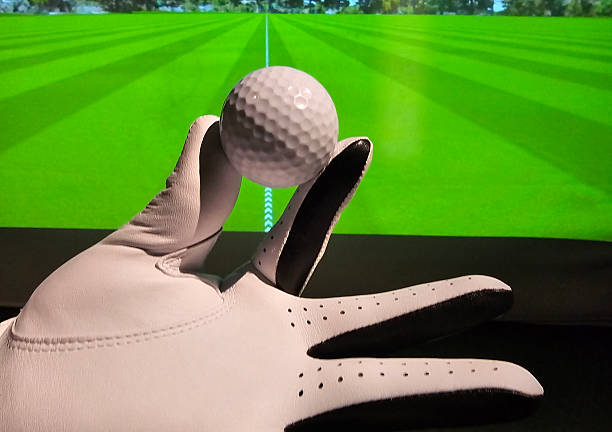 istock Golf ball held in hand with virtual golf course in background during indoor practice session at sports facility in evening concept 2250445029