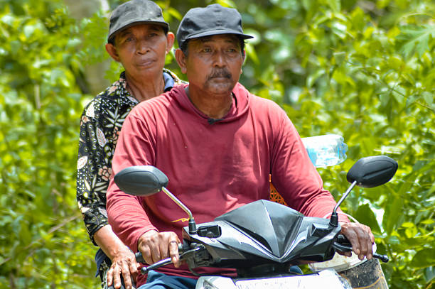 istock Village Couple Riding Scooter Together With Relaxed Expression on a Sunny Day 2250449730