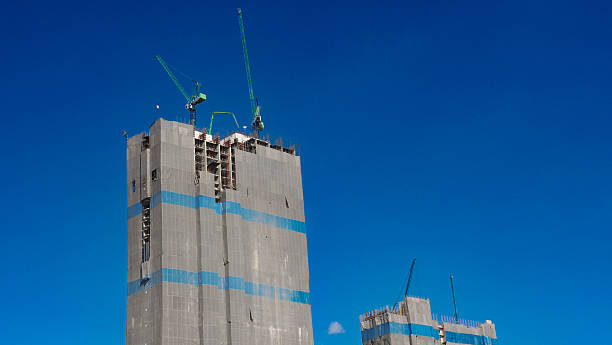 istock High-Rise Building Under Construction with Green Cranes against a Solid Blue Sky 2250455874