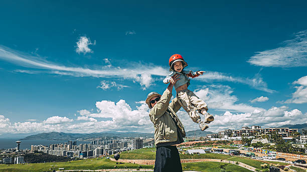 Young asian father and son having fun outdoors in a park of mountain top. Dad lifted his son up. Dali, Yunnan province, China.