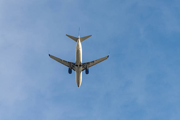 istock Passenger airplane flying on blue sky, low angle view 2250458902