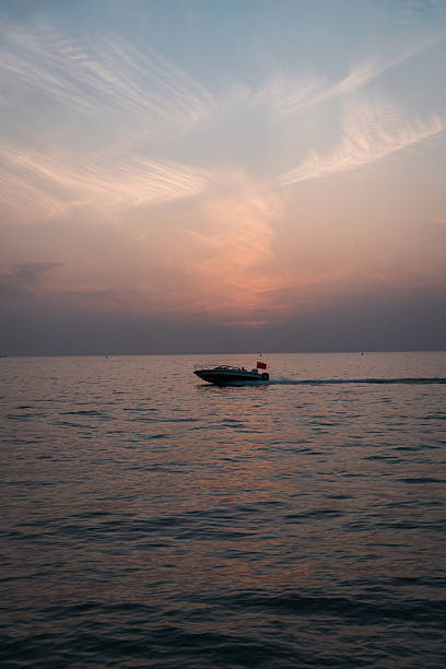 istock Sunset over the sea with a speedboat cruising 2250460169