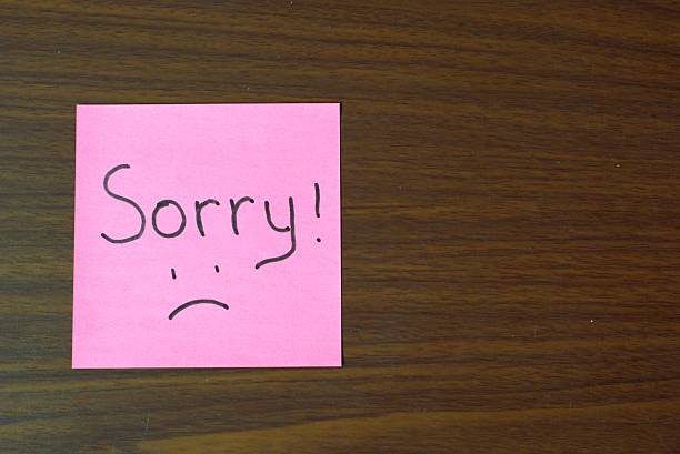 istock sorry handwritten note on pink sticky paper 2250468078