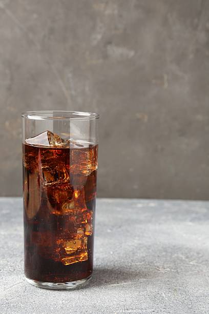 istock Refreshing cola with ice cubes in glass on light textured table against grey background, closeup. Space for text 2250470784