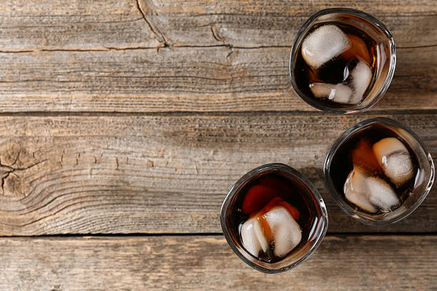 istock Refreshing cola with ice cubes in glasses on wooden table, flat lay. Space for text 2250471061