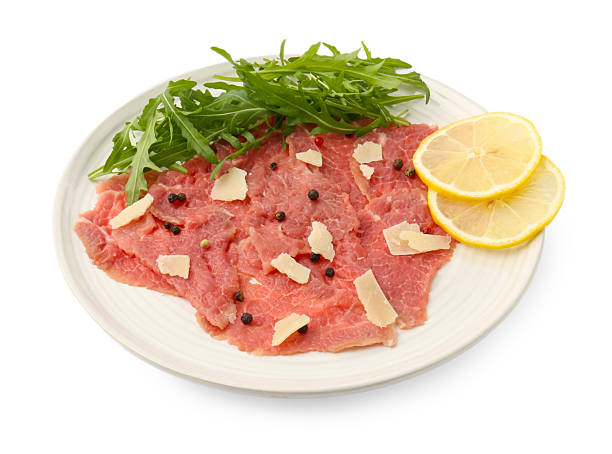 Fresh beef carpaccio with arugula, lemon and cheese isolated on white