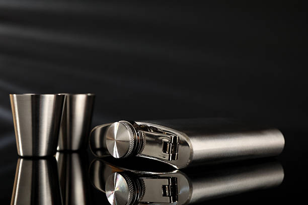 istock Hip flask and cups on black mirror surface, closeup 2250478383
