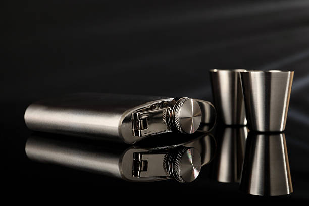 istock Hip flask and cups on black mirror surface, closeup 2250478414