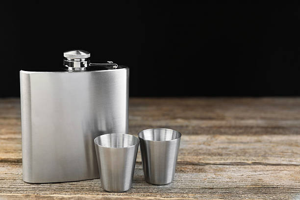 istock Hip flask and cups on wooden table, space for text 2250478535