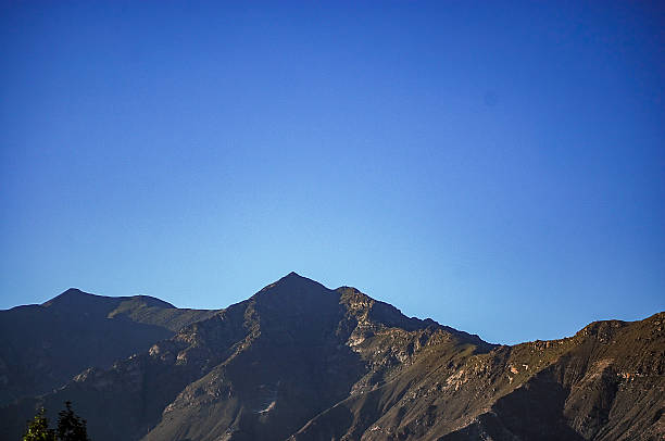 A clear view of a mountain range with sharp peaks under a bright blue sky, showcasing natural mountainous landscape.
